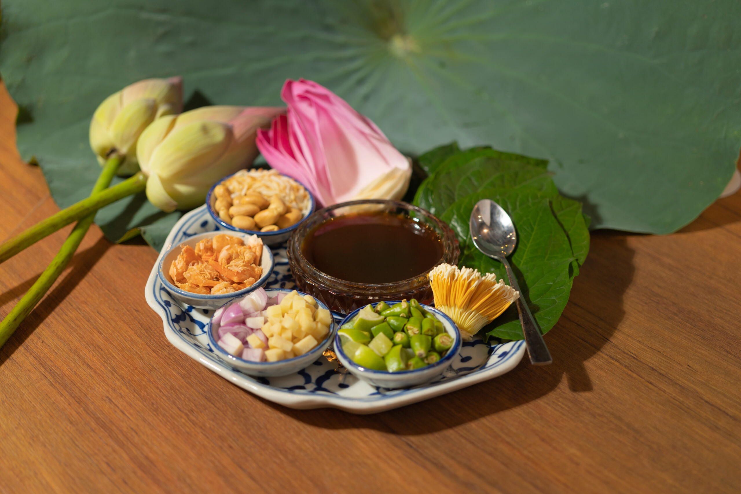 A set of Miang kham, Thai appetizer food with Lotus flower and leaf wrapped on traditional ceramic serving dish.
